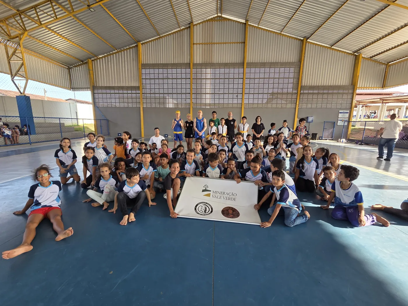 Dezenas de alunos de escola pública do projeto Caminho da Mestria com a faixa da Mineração Vale Verde